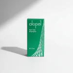 Зелена картонна упаковка шампуню Alopel. Спеціалізований засіб для зупинки випадіння волосся та стимуляції його росту.