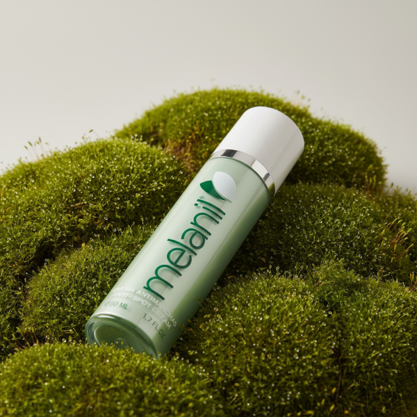 Естетичне фото флакона крему Melanil на зеленому моху, що підкреслює натуральні компоненти засобу.