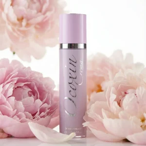 Естетичне фото флакона крему Ококсин серед свіжих рожевих півоній.