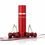 Червоний флакон крему для обличчя Retorna в оточенні стиглих черешень.