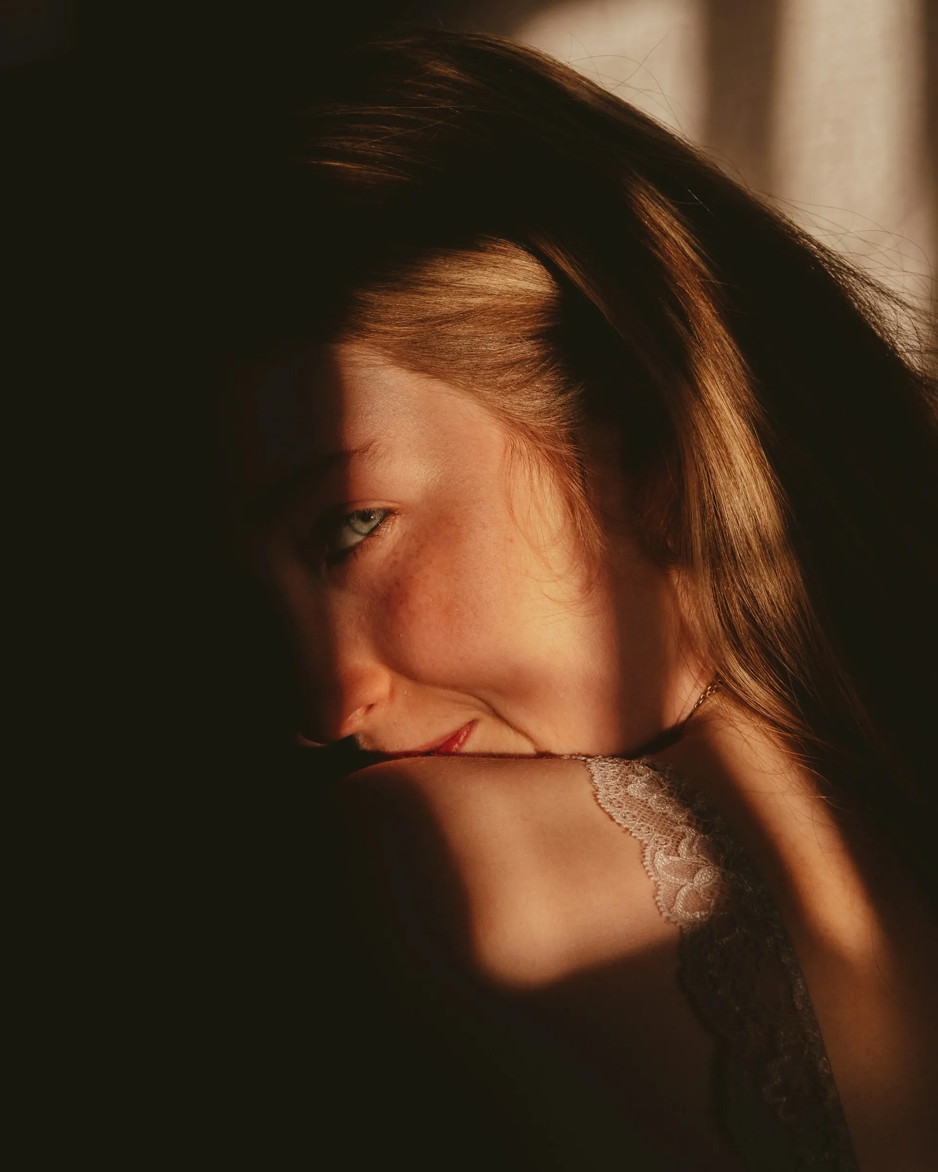 Портрет усміхненої жінки, обличчя якої освітлене природним сонячним світлом, що створює контрастні тіні. Ілюстрація догляду за пігментованою шкірою.